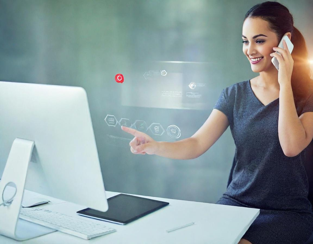 Femme souriante au téléphone, utilisant un ordinateur à un bureau moderne.